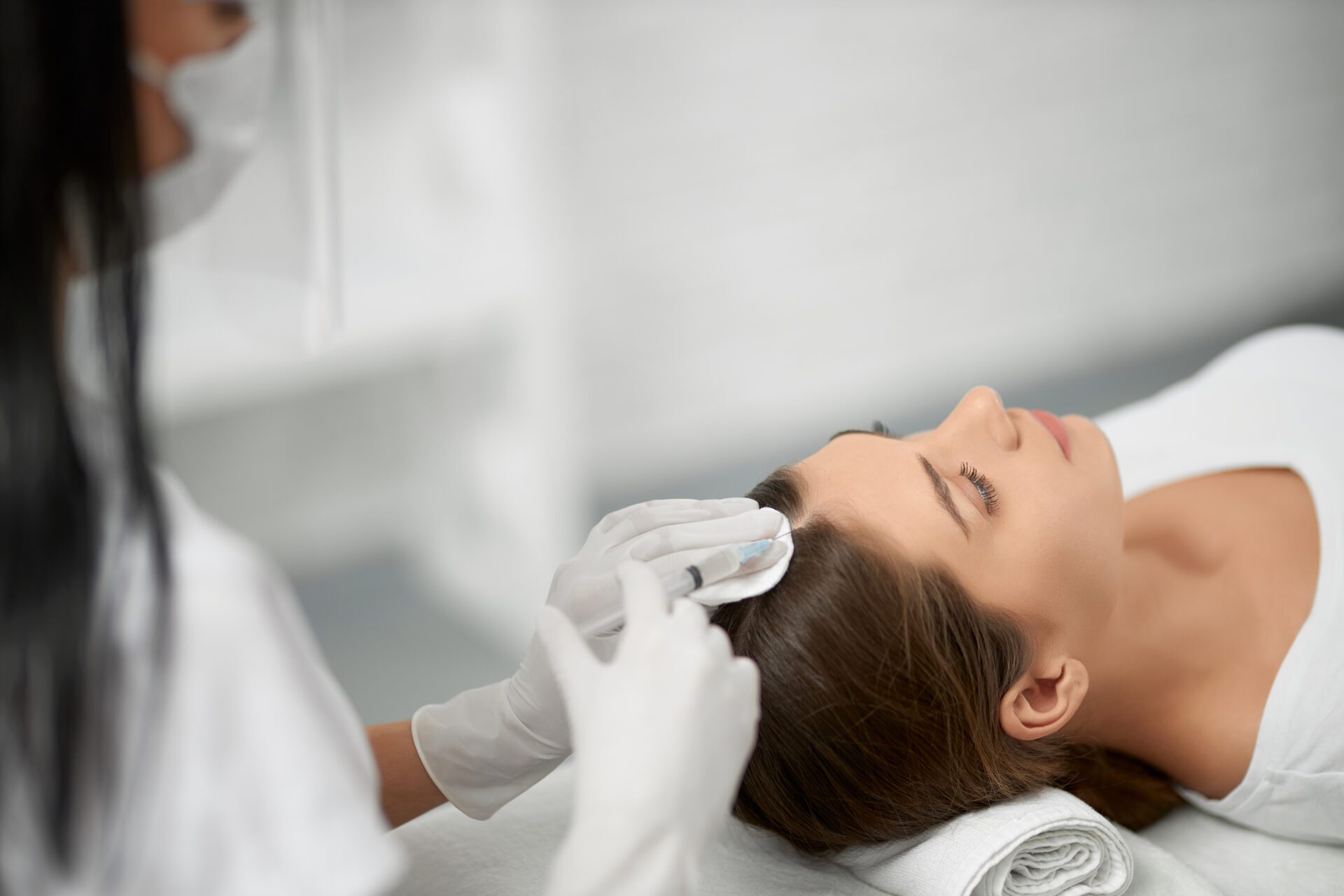 Beautician in protective mask doing procedure for hair.